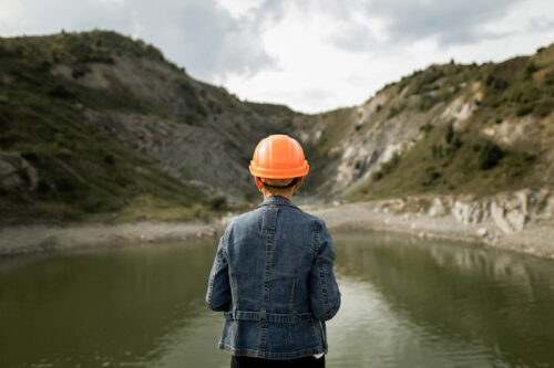 Female engineer watching on the lake in the quarry. View from behind